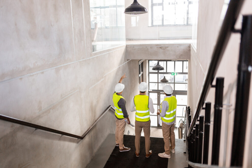architects in helmets with blueprints at office